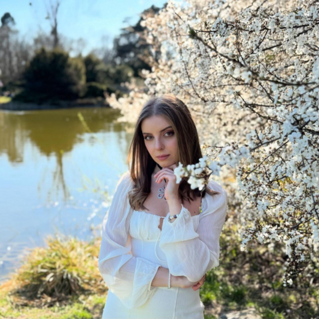 穿着白色连衣裙的女性在湖边和花树前