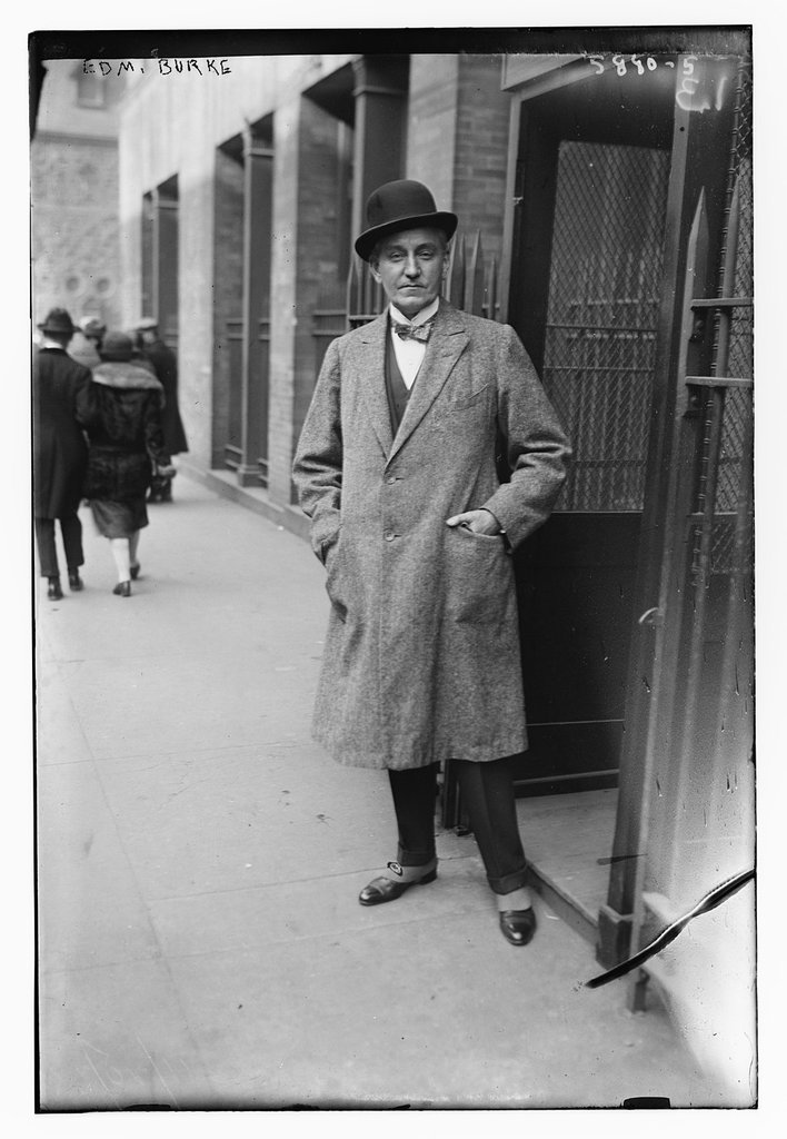 都市男性身着灰色羊毛大衣漫步混凝土建筑群