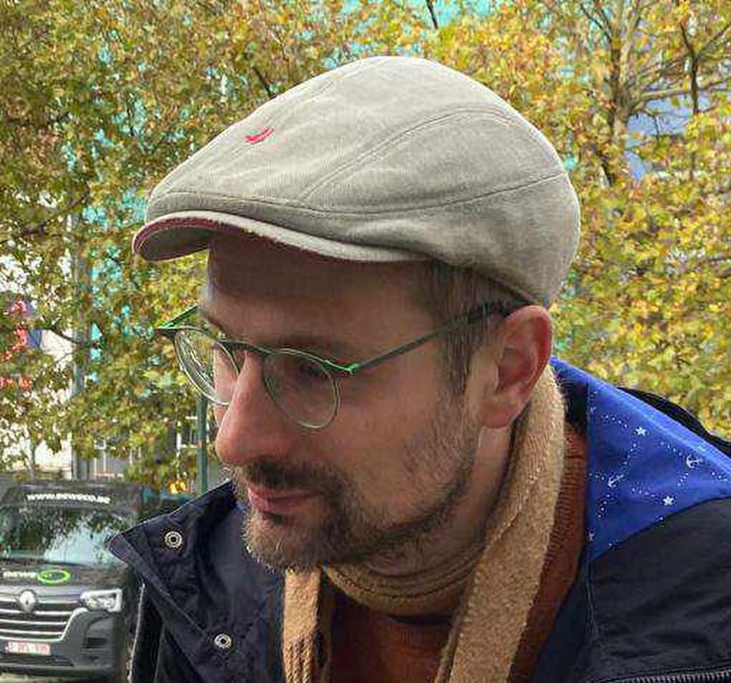 戴帽子和眼镜的男士户外肖像，展现自然光线下的穿搭